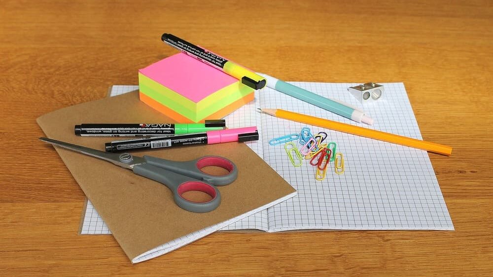 Papelaria Fofa foto da mesa com caderno, lápis, canetinha, marca texto, tesoura e bloco de anotações coloidos